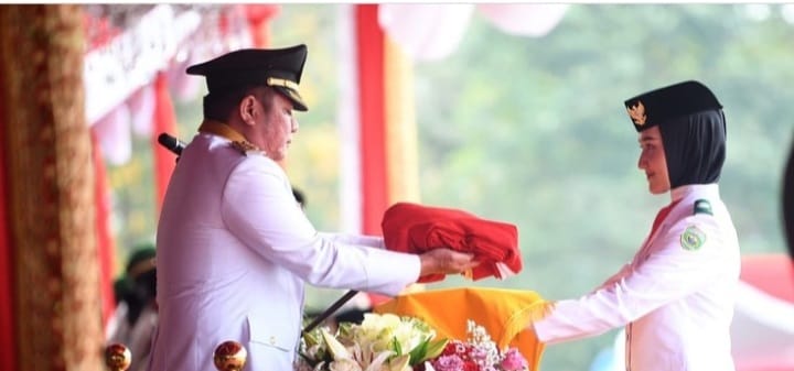 Bertindak sebagai inspektur upacara, Gubernur Sumsel Herman Deru menyerahkan sangsaka merah putih kepada pembawa baki Gesya Bilbina Adrein pada upacara HUT RI di Griya Agung, Palembang, Kamis (17/8/2023). Foto : Humas Pemprov Sumsel.