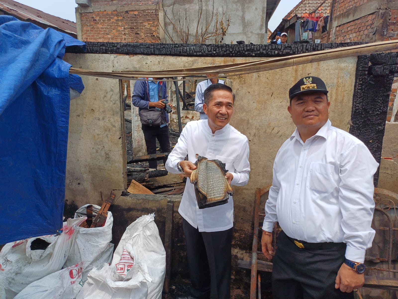 Pj Walikota Palembang, Ratu Dewa menunjukkan Alquran yang relatif utuh di puing-puing kebakaran rumah di 7 Ulu, Jumat (10/11/2023). Foto : Sumselheadline/Ela