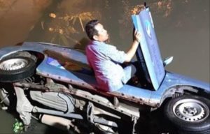 Sopir dan taxi blue bird nyemplung ke sungai di belakang Poltek Sriwijaya, Minggu (12/11/2023). Foto : Screenshot medsos.