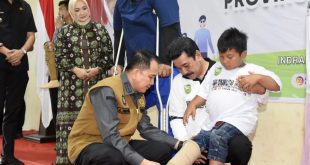 Pj Gubernur Sumsel, Agus Fatoni memasang alat bantu pada seorang disabilitas di Inderalaya, Kamis (21/12/2023). Foto: Humas Pemprov Sumsel.