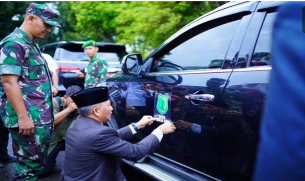 Pj Bupati Muba, Apriyadi memasang stiker khusus pada mobil dinasnya, sebagai upaya pengamanan aset daerah. Foto: Dok Dinkominfo Muba.