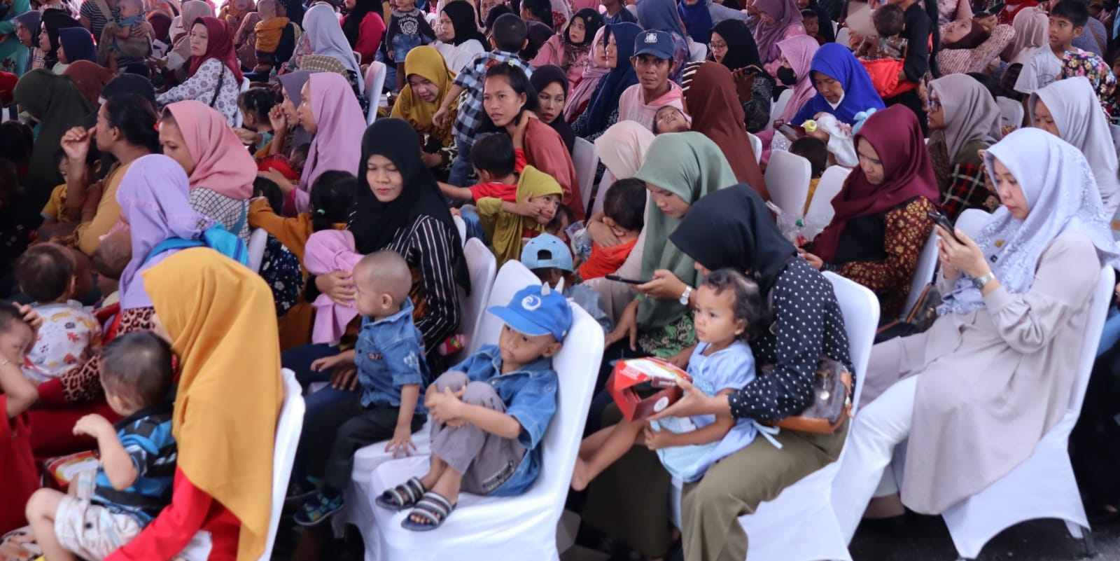Sejumlah ibu-ibu dan anak yang mendapat paket makanan dan minuman bergizi dari Pemkot Palembang, Jumat (26/1/2024). Foto: Sumselheadline/Pitria.