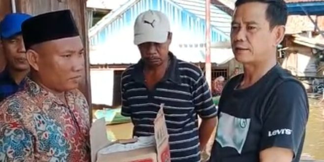 Ketum HKB Ulbamas Palembang, Nasrullah menyerahkan secara simbolis paket bantuan korban banjir kepada Kades Ulak Embacang, Nur'aidin Hasanuddin, Minggu (21/1//2024). Foto: Dok HGB Ulbamas.