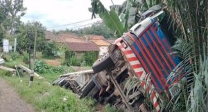 Sebuah truk trailer bermuatan paku bumi, terguling di pinggir jalan Desa Pulau Harapan, Banyuasin, Senin (5/2/2024). Foto: Tribunsumsel.com.