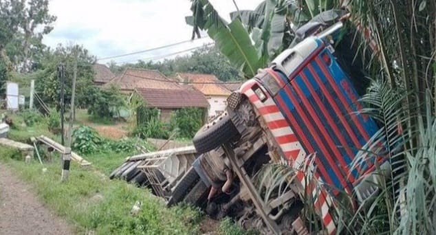 Sebuah truk trailer bermuatan paku bumi, terguling di pinggir jalan Desa Pulau Harapan, Banyuasin, Senin (5/2/2024). Foto: Tribunsumsel.com.