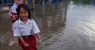 Untuk menuju sekolah, para murid harus lepas sepatu dan angkat rok di kawasan Jalan R Soekamto, Palembang, Libur lebaran 1445 H, sekolah akan libur selama dua pekan. Foto: Dok Sumselheadline/Pitria.