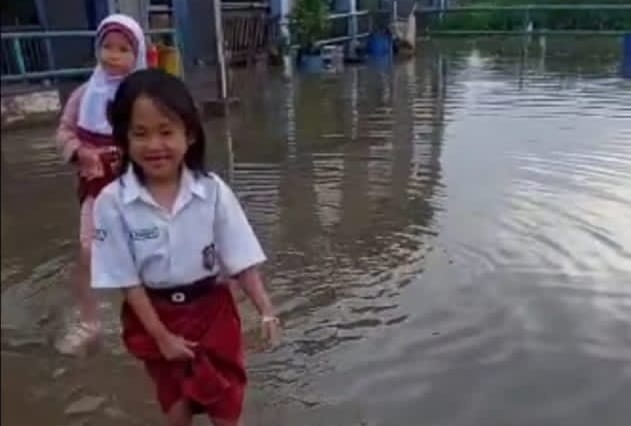Untuk menuju sekolah, para murid harus lepas sepatu dan angkat rok di kawasan Jalan R Soekamto, Palembang, Libur lebaran 1445 H, sekolah akan libur selama dua pekan. Foto: Dok Sumselheadline/Pitria.