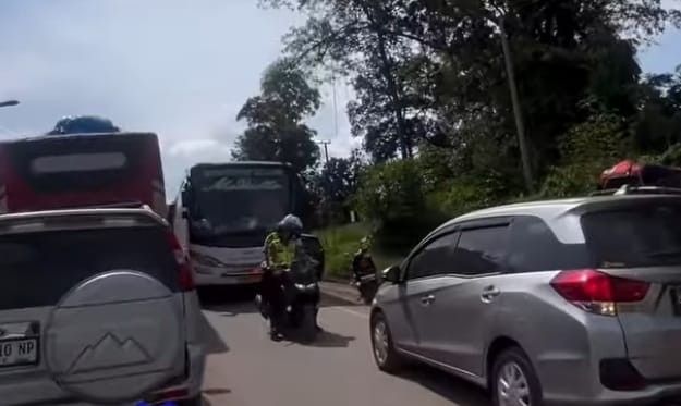 Tampak seorang polisi memaksa sopir memundurkan kendaraan yang menerobos jalur berlawanan, sehingga menjadi penyebab macet makin parah, Sabtu (6/4/2024) lalu. Foto: screenshot medsos.