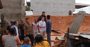 Camat Babat Toman Heru Kharisma (baju putih) melaihat langsung kondisi pagar bangunan yang menimpah bedeng warga. Foto: Kominfo Muba.