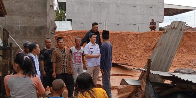 Camat Babat Toman Heru Kharisma (baju putih) melaihat langsung kondisi pagar bangunan yang menimpah bedeng warga. Foto: Kominfo Muba.