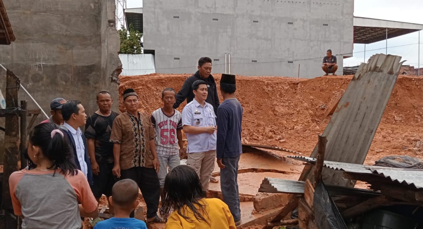 Camat Babat Toman Heru Kharisma (baju putih) melaihat langsung kondisi pagar bangunan yang menimpah bedeng warga. Foto: Kominfo Muba.