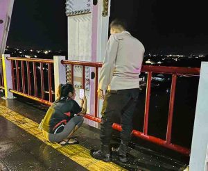 Seorang anggota polisi saat membujuk Rosa yang mau bunuh diri di Jembatan Musi II, Palembang, Rabu (12/6/2024) malam. Foto: Dok Polsek IB II.