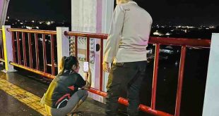Seorang anggota polisi saat membujuk Rosa yang mau bunuh diri di Jembatan Musi II, Palembang, Rabu (12/6/2024) malam. Foto: Dok Polsek IB II.