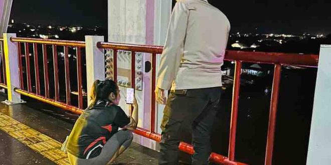 Seorang anggota polisi saat membujuk Rosa yang mau bunuh diri di Jembatan Musi II, Palembang, Rabu (12/6/2024) malam. Foto: Dok Polsek IB II.