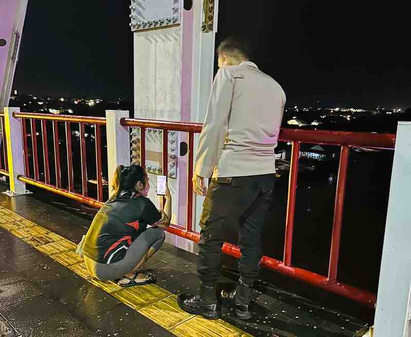 Seorang anggota polisi saat membujuk Rosa yang mau bunuh diri di Jembatan Musi II, Palembang, Rabu (12/6/2024) malam. Foto: Dok Polsek IB II.