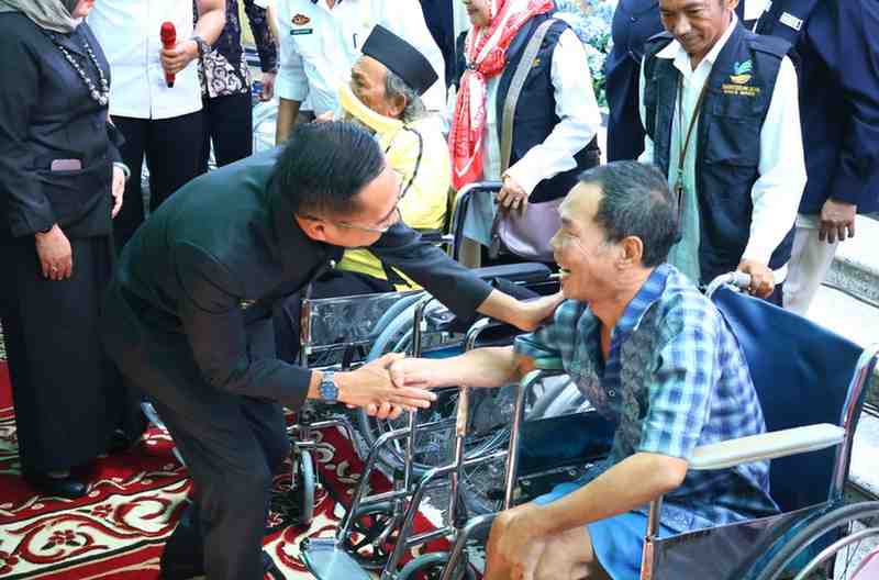 Pj Walikota Palembang, Ratu Dewa berdialog dengan seorang disabilitas, setelah memberikan bantuan kursi roda, Kamis (13/6/2024). Foto: Kominfo Palembang.