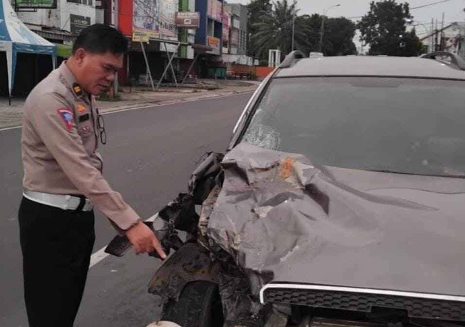 Seorang Polantas menunjukkan bagian mobil Chevrolet Captiva BG 1340AH yang menabrak pengendara motor, Selasa (4/6/2024). Foto: Sumselheadlline/Ela.
