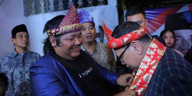 PJ Walikota Palembang, Damenta mendapat kalungan kembang songket dari Yan Coga, Ketua Raja Sriwijaya di 24 Ilir. Minggu (7/7/2024). Foto: Kominfo Palembang.
