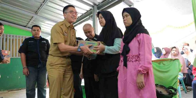 Sekda Palembang, Ratu Dewa memberikan bantuan kepada keluarga penyandang tuna netra Palembang, Selasa (2/7/2024). Foto: Sumselheadline/Pitria.