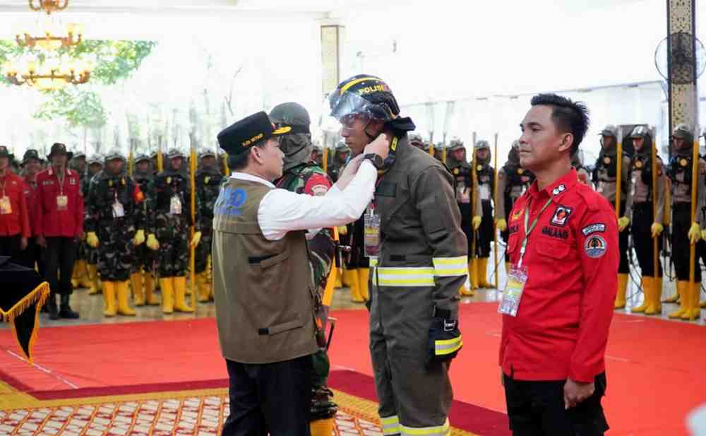 Pj Gubernur Sumsel, Elen Setiadi secara simbolis memasang pakaian kerja tim seiaga Karhutlah yang mengikuti pelatihan di Griya Agung, Kamis (25/7/2024). Foto: Humas Pemprov Sumsel.