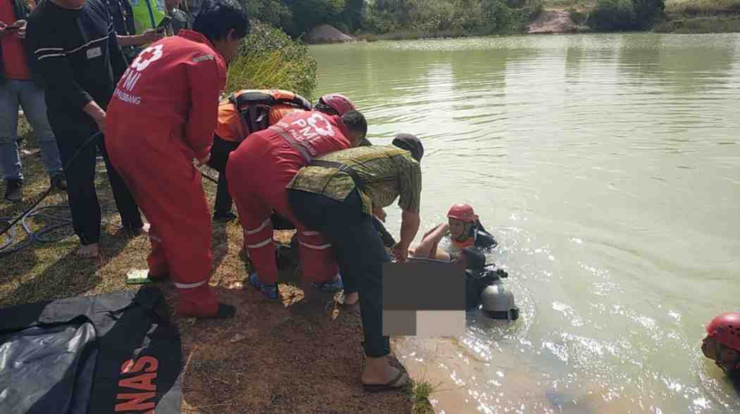 Sejumlah petugas yang tengah mengevakuasi bocah yang tenggelam di bekas galian, dekat Asrama Haji Palembang, Sabtu (27/7/2024). Foto: Dok Basarnas Palembang.