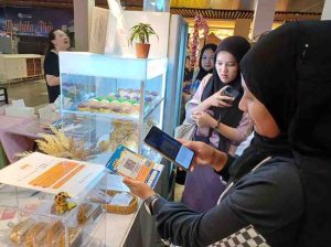 Warga uang melakukan pembayaran menggunakan qris di toko. Foto: Sumselheadline/Pitria.