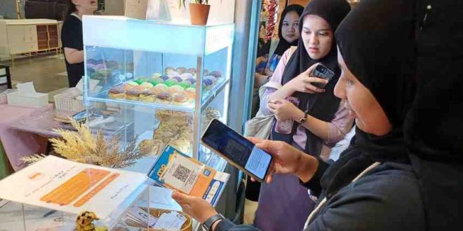 Warga uang melakukan pembayaran menggunakan qris di toko. Foto: Sumselheadline/Pitria.