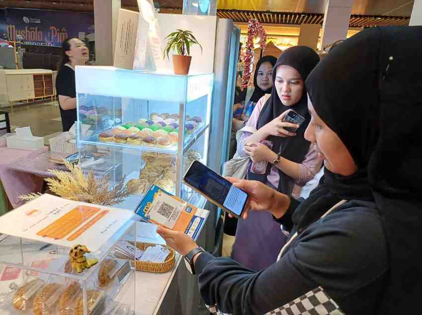 Warga uang melakukan pembayaran menggunakan qris di toko. Foto: Sumselheadline/Pitria.