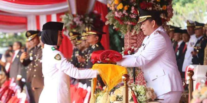 PJ Gubernur Sumsel, Elen Setiadi menyerahkan bendera kepada pengerek bendera upacara HUT Kemerdekaan RI ke-79, Sabtu (17/8/2024). Foto: Humas Pemprov Sumsel.