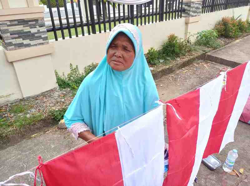 Asmawati dengan jualan bendera merah putih di kawasan DPRD Sumsel, Palembang, Minggu (11/8/2024). Foto: Sumselheadline/Pitria.