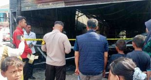 Warga dan petugas menyaksikan puiting-puing bekas kebakaran di Toko Olahraga di Gandus Palembang, Selasa (13/8/2024). Foto: Sumselheadline/Ela.