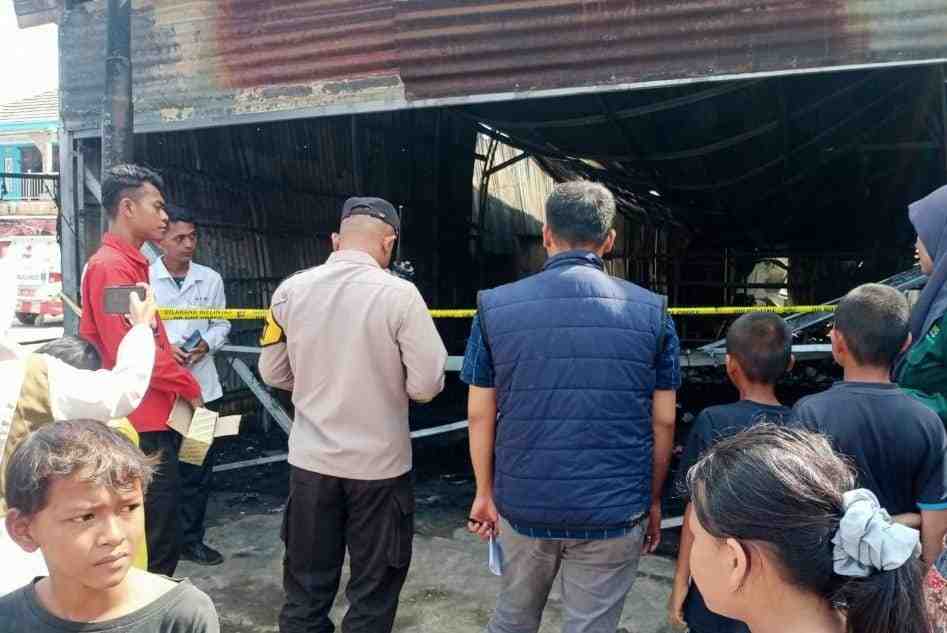 Warga dan petugas menyaksikan puiting-puing bekas kebakaran di Toko Olahraga di Gandus Palembang, Selasa (13/8/2024). Foto: Sumselheadline/Ela.