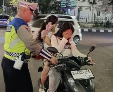 Polisi menghentikan dua remaja putri yang berkendaraan yak menggunakan helm di Jl Sudirman Palembang, Sabtu (38/2024). Foto: Dok Polisi.