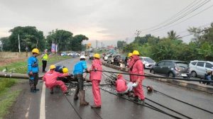 Petugas mengevakuasi tiang listrik yang melintang di jalan Palembang-Inderalaya, Ogan Ilir, Minggu (10/11/2024). Foto: Sripoku.com.
