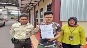 Jemmy, menunjukkan bukti laporan terhadap babysister yang dituduh menganiaya anaknya. Foto: tribunsumsel.com.