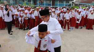 Walikota Palembang, Ratu Dewa secara simbolis memasang seragam kepada salah satu murid SDN 200 Palembang, sebagai tanda mulai dibagikannya seragam gratis dari Pemkot Palembang, Senin (14/7/2025). Foto: Kominfo Palembang.