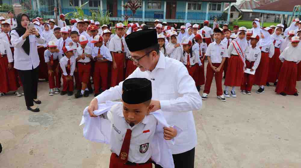 Walikota Palembang, Ratu Dewa secara simbolis memasang seragam kepada salah satu murid SDN 200 Palembang, sebagai tanda mulai dibagikannya seragam gratis dari Pemkot Palembang, Senin (14/7/2025). Foto: Kominfo Palembang.