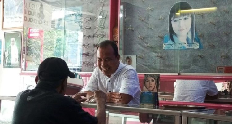 Uda Andi, Owner Optik Sriwijaya, sedang melayani pelanggan yang datang untuk membeli kacamata. (SUMSELHEADLINE.COM/OYONG)