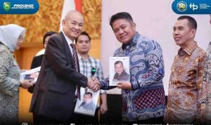 Chairul S Matdiah menyerahkan buku biografi kepada Gubernur Sumsel Herman Deru pada acara launching di Ballroom Hotel Aryaduta Palembang, Sabtu (23/8/2025). Foto: IST