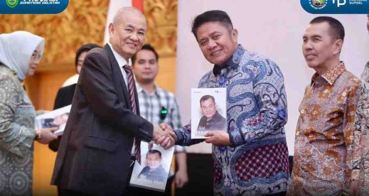 Chairul S Matdiah menyerahkan buku biografi kepada Gubernur Sumsel Herman Deru pada acara launching di Ballroom Hotel Aryaduta Palembang, Sabtu (23/8/2025). Foto: IST