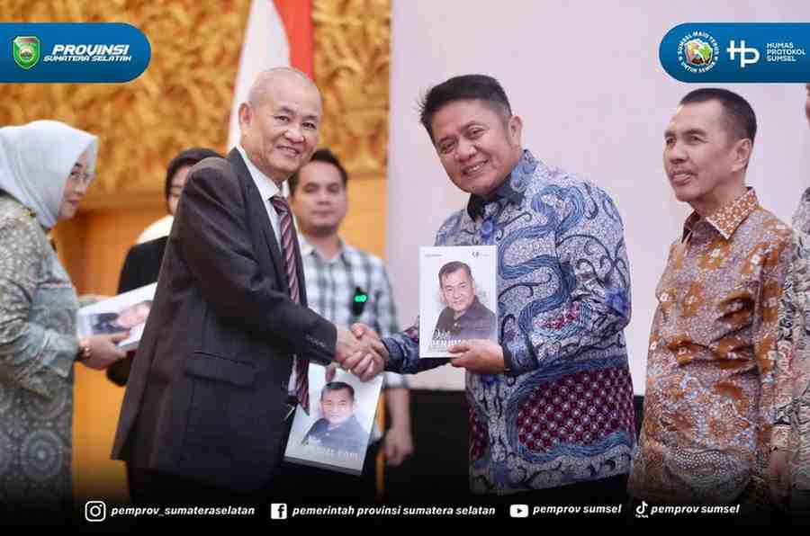 Chairul S Matdiah menyerahkan buku biografi kepada Gubernur Sumsel Herman Deru pada acara launching di Ballroom Hotel Aryaduta Palembang, Sabtu (23/8/2025). Foto: IST