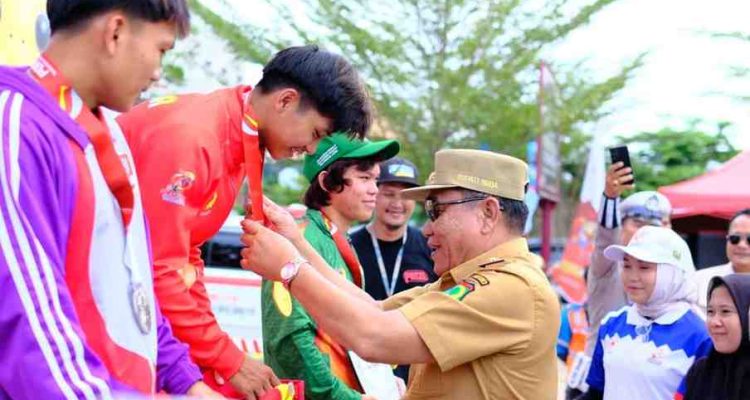 Bupati Muba, HM Toha mengalungkan medali emas pada atlet penerima medali emas panjat tebing Porprov, Selasa (21/10/2025). Foto: Kominfo Muba.