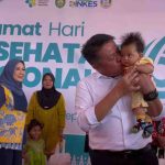 Gubernur Sumsel, Herman Deru menggendong bayi pada peringatan Hari Kesehatan Nasional (HKN) ke-61 di Desa Merah Mata, Kecamatan Banyuasin I, Kamis (27/11/2025). Foto: Humas Pemprov Sumsel.