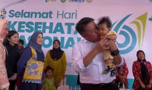 Gubernur Sumsel, Herman Deru menggendong bayi pada peringatan Hari Kesehatan Nasional (HKN) ke-61 di Desa Merah Mata, Kecamatan Banyuasin I, Kamis (27/11/2025). Foto: Humas Pemprov Sumsel.