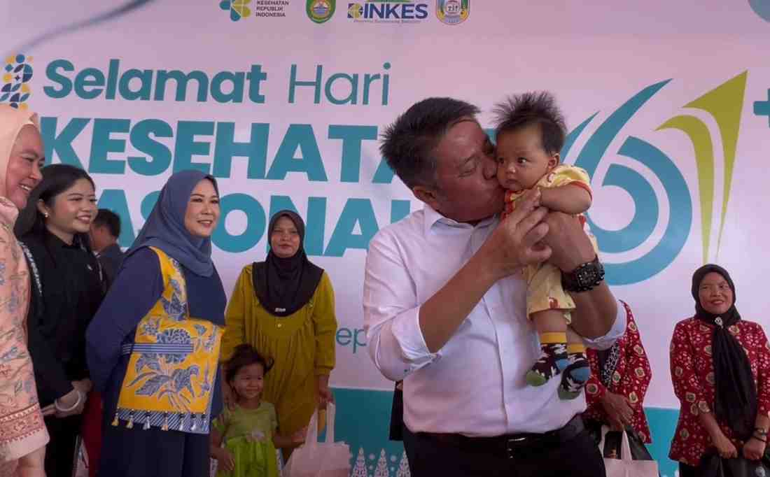 Gubernur Sumsel, Herman Deru menggendong bayi pada peringatan Hari Kesehatan Nasional (HKN) ke-61 di Desa Merah Mata, Kecamatan Banyuasin I, Kamis (27/11/2025). Foto: Humas Pemprov Sumsel.