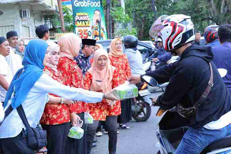 Kadiskominfo Palembvang, Adi Zahri mendampingi Ketua Dharma Wanita Persatuan Dinas Kominfo Kota Palembang membagi takjil kepada sejumlah pengendara. Foto: Kominfo Palembang.