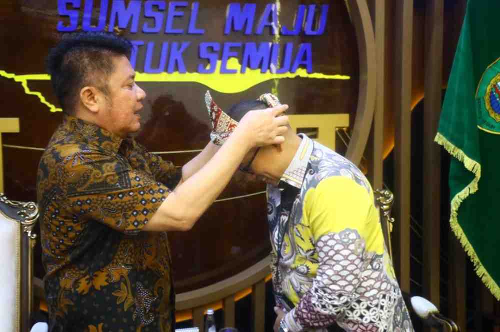 Gubernur Sumatera Selatan, Dr. H. Herman Deru memasangkan tanjak kepada General Manager PT PLN (Persero) Unit Induk Distribusi Sumatera Selatan, Jambi, dan Bengkulu (UID S2JB), Diksi Erfani Umar, di Ruang Tamu Gubernur Sumsel, Jumat (17/4/2026). Foto: Humas Pemprov Sumsel.