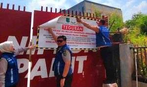 Petugas memasang stiker pada reklame yang tak bayar pajak. Foto: Kominfo Muba.