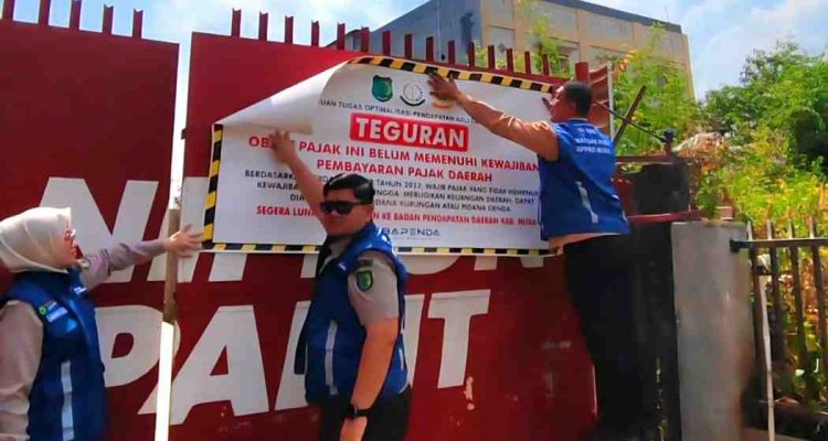 Petugas memasang stiker pada reklame yang tak bayar pajak. Foto: Kominfo Muba.