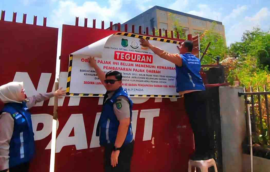 Petugas memasang stiker pada reklame yang tak bayar pajak. Foto: Kominfo Muba.